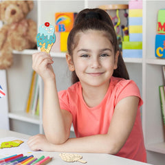 Young girl holding a colorful ice cream cone craft in a classroom setting