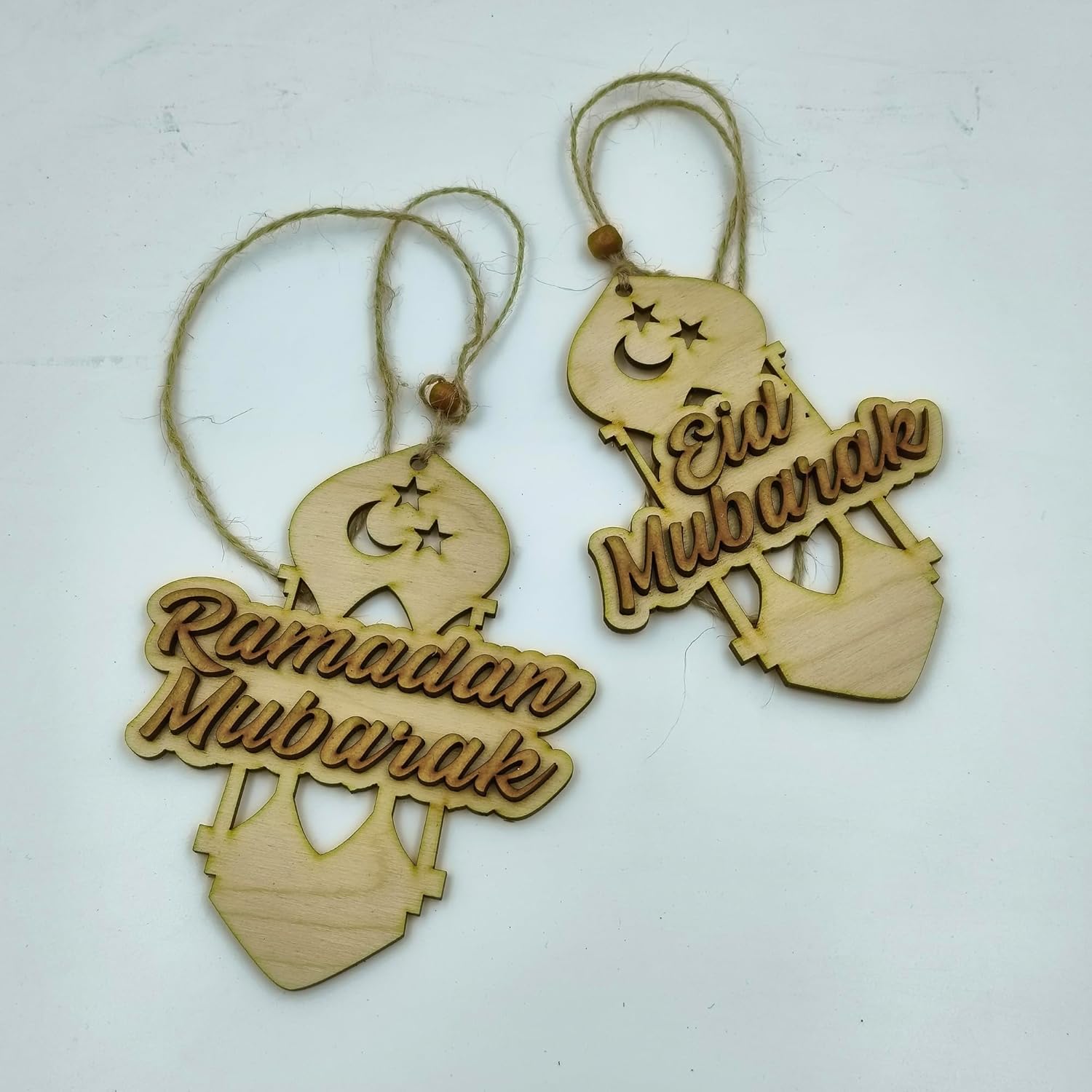 Two wooden 'Ramadan Mubarak' and 'Eid Mubarak' decorations on a white background.