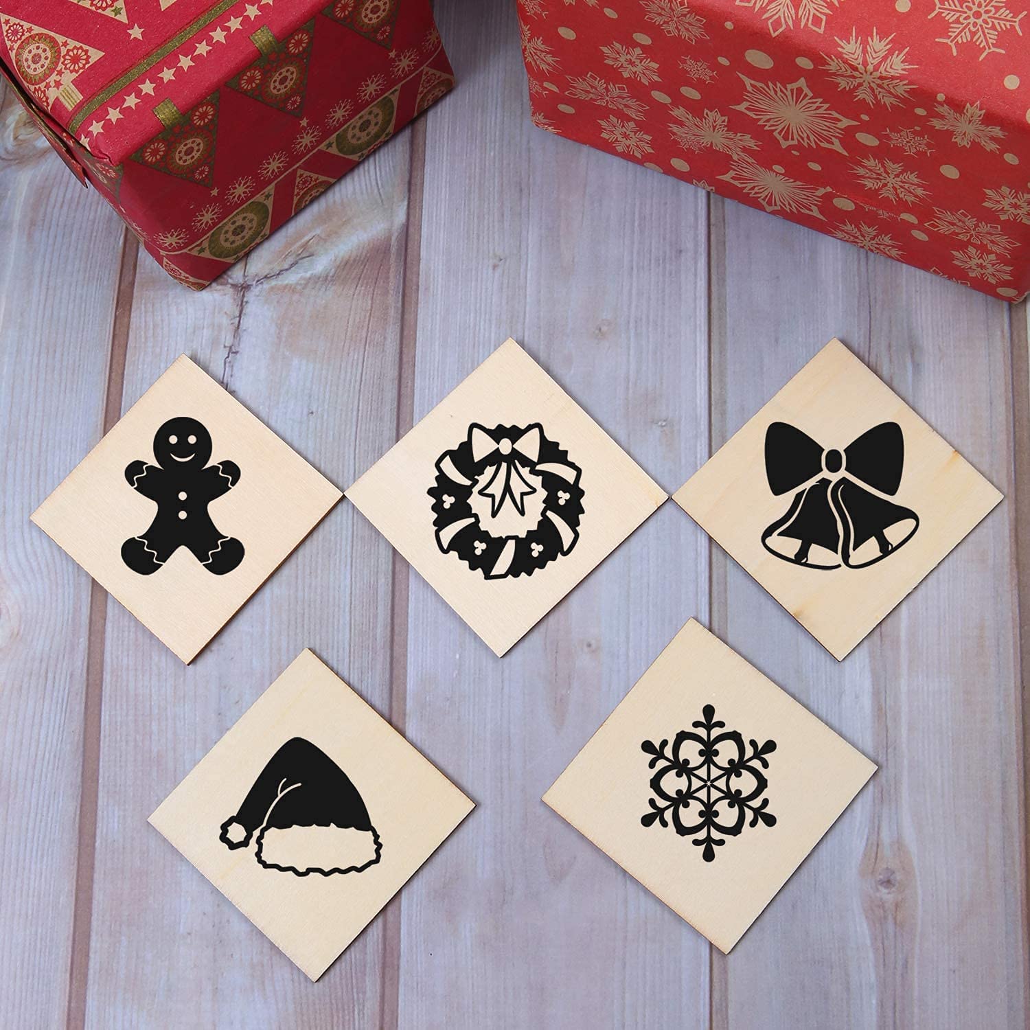 Set of Christmas-themed rubber stamps on a wooden surface with gift boxes in the background.