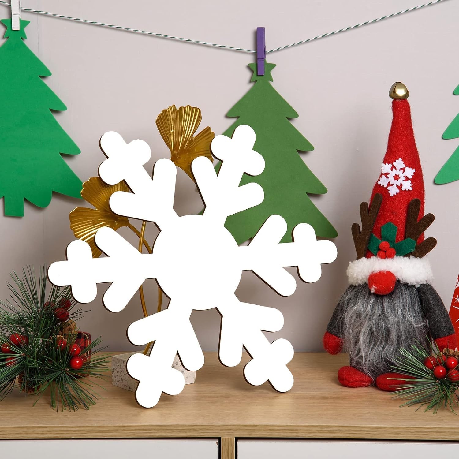 Decorative items including a large white snowflake, Christmas trees, and a gnome on a wooden surface.