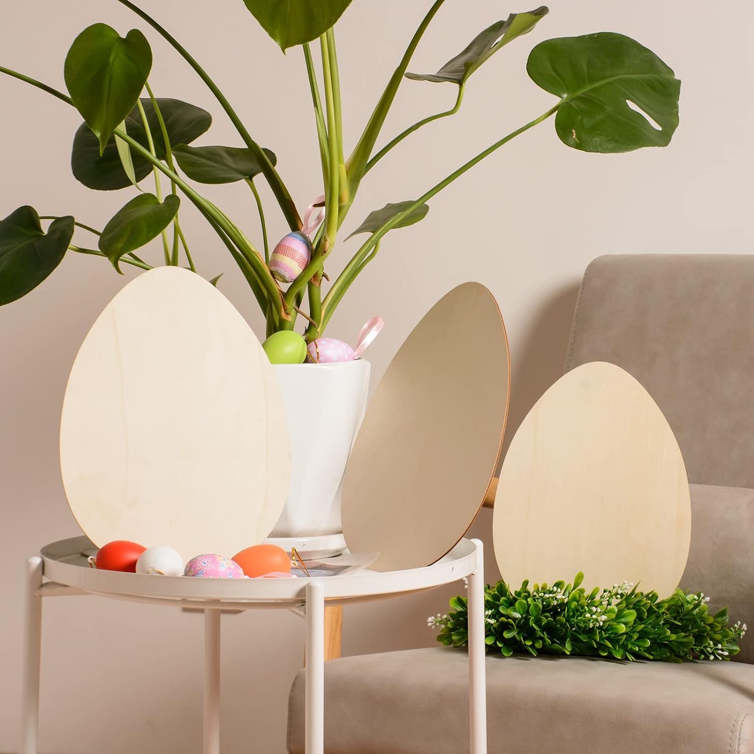 Decorative egg-shaped lamps on a table with a plant and colorful eggs in the background.