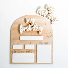 Wooden plaque with cut-out letters spelling 'my first day' and other text on a white background