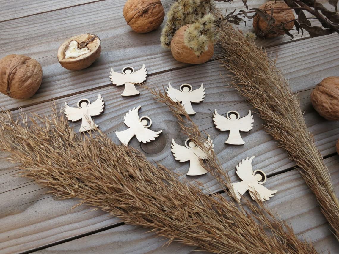 Wooden angel-shaped pendants on a wooden surface with dried plants and nuts.