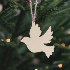 White dove ornament hanging on a Christmas tree with blurred lights in the background