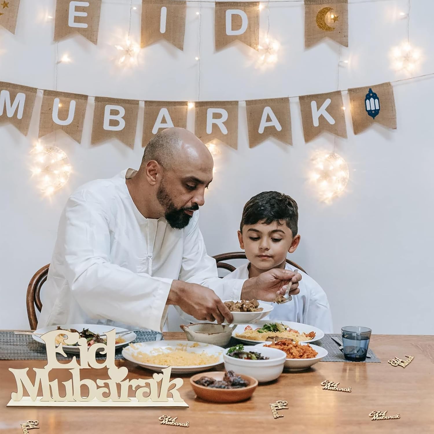Man and child sitting at a table with food, celebrating Eid Mubarak.
