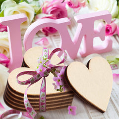 Pink 'LOVE' letters with wooden hearts and ribbons on a floral background