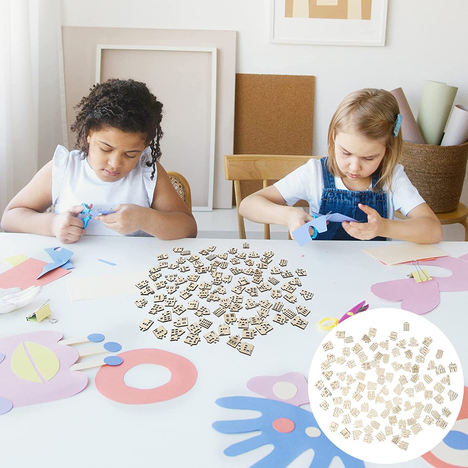 Two children sitting at a table with craft materials and alphabet letters.