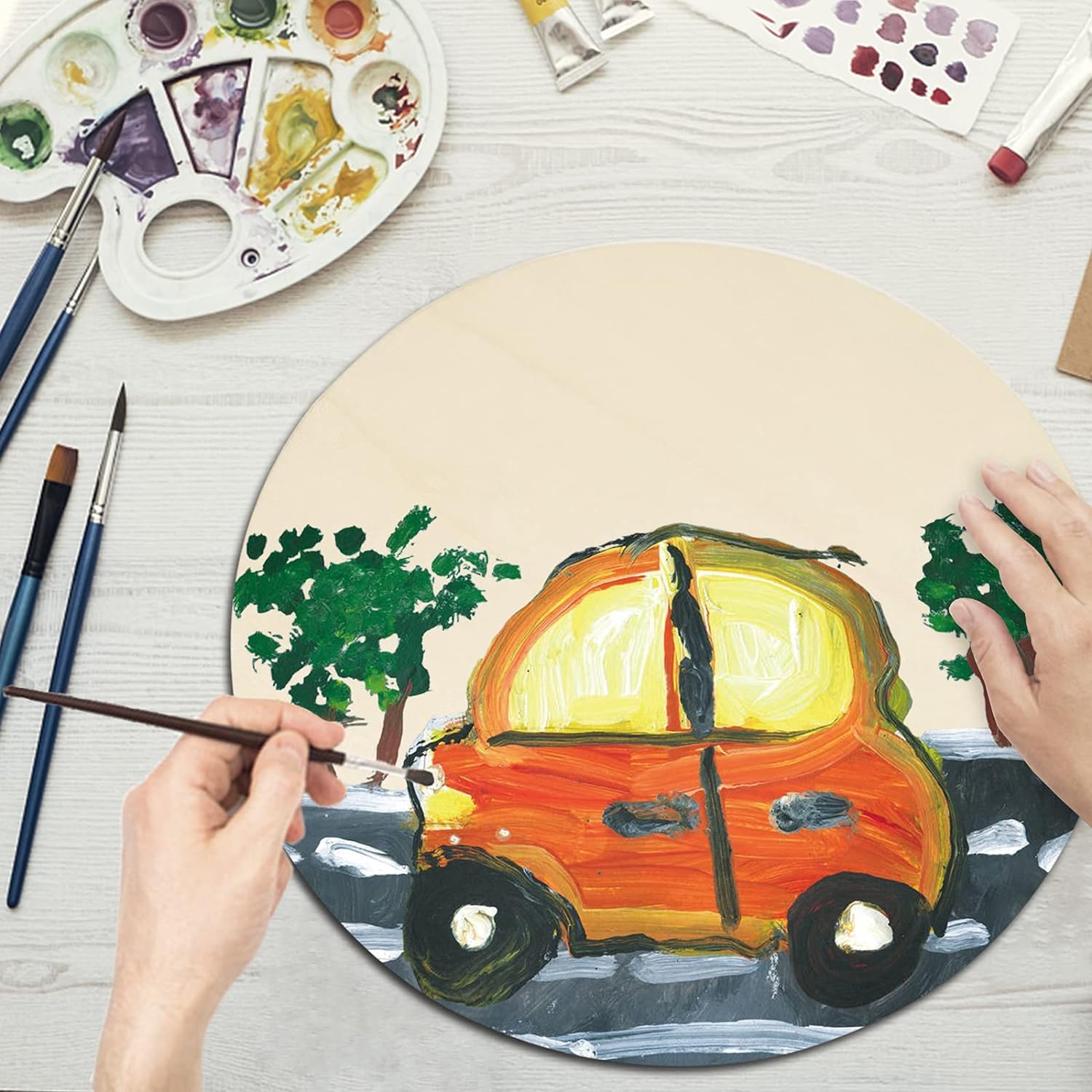 Person painting a car on a round canvas with art supplies around