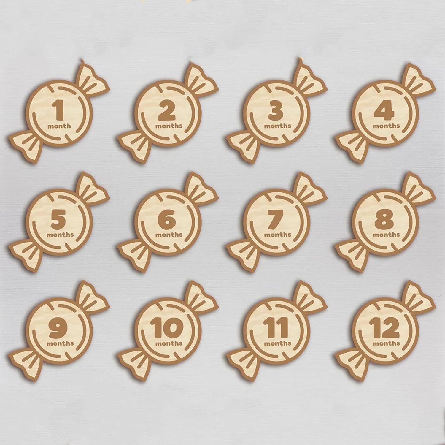 Wooden baby milestone markers with numbers 1 to 12 months on a light gray background