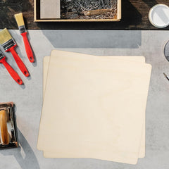 Two beige placemats on a gray surface with red paintbrushes and a wooden box of pins.