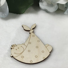 Wooden cutout of a baby in a crib with a white blanket on a light background