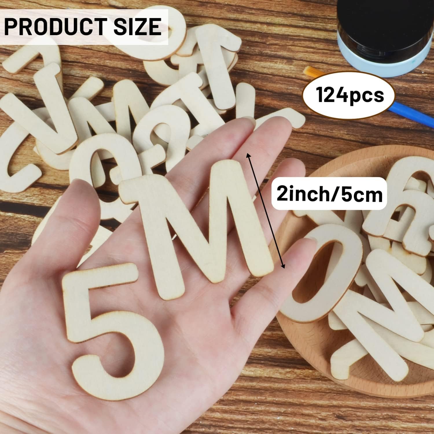 Wooden letters and numbers on a wooden surface with a hand holding a letter 'M'.