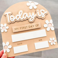 Children's first day of school sign with flowers and text on a beige background