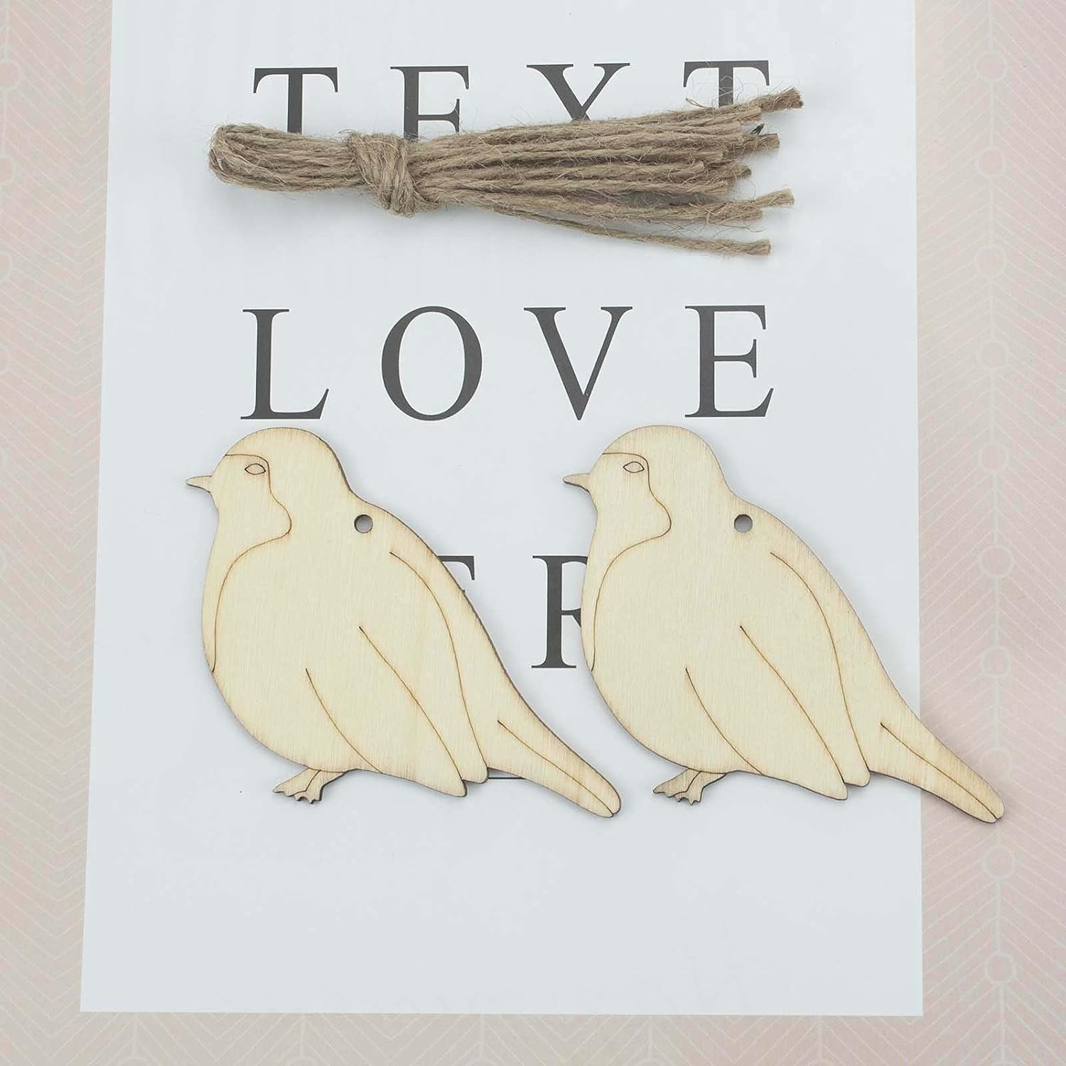 Two wooden bird shapes with twine on a card with 'TEXT LOVE' printed on it.