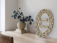 Decorative wall art with 'Ramadan Kareem' text on a light wooden surface with a vase and books.