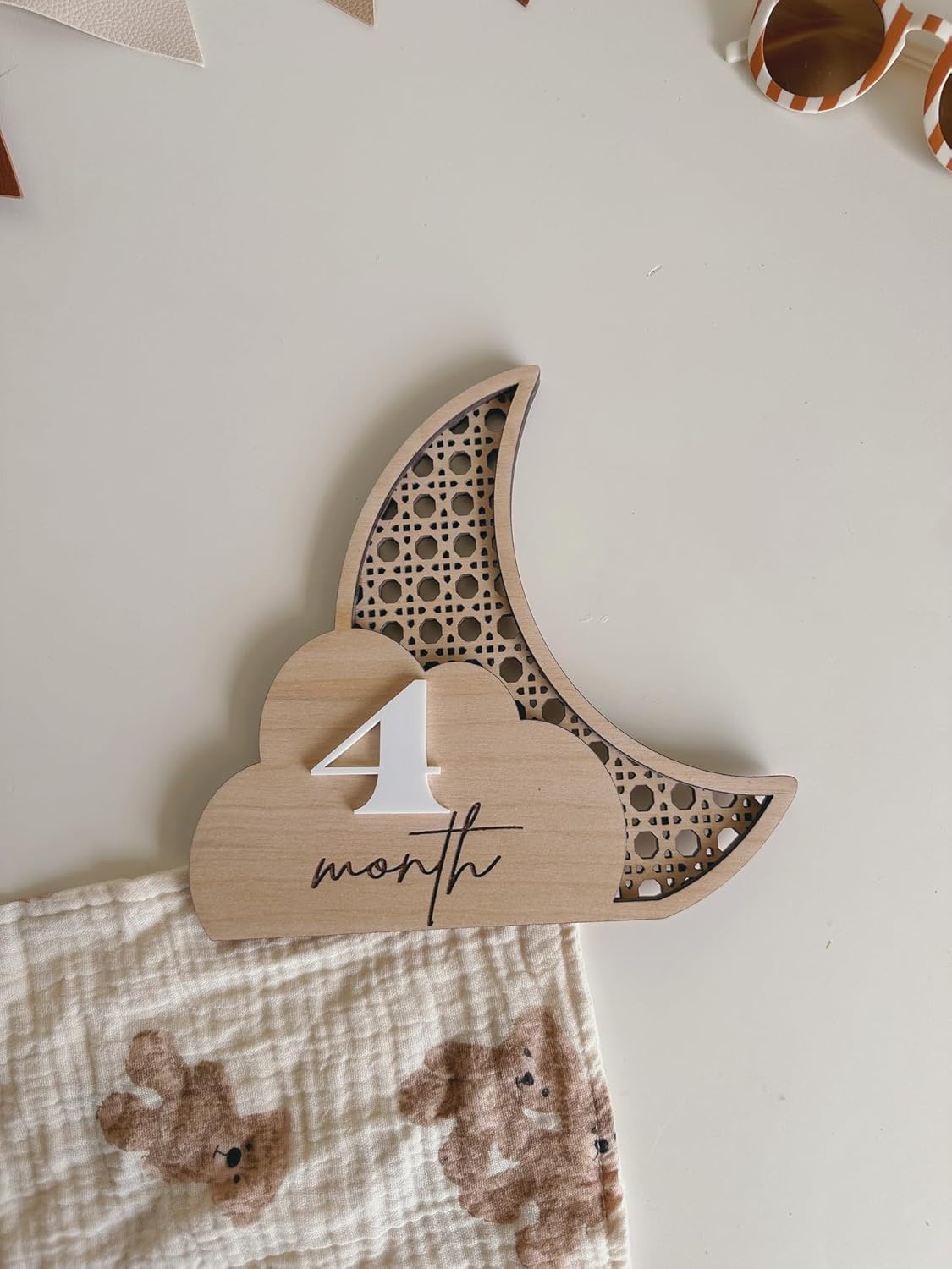 Wooden baby milestone card with '4th month' on a white background