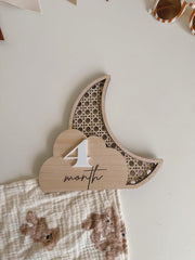 Wooden baby milestone card with '4th month' on a white background