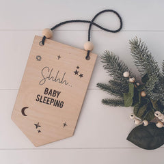 Wooden sign with 'Shhh... Baby Sleeping' text on a white background with decorative elements.