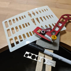 Set of tools including a red tool, white ruler, and Sharpie marker on a wooden surface.