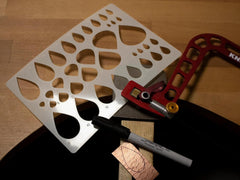 Metal cutting template with a marker and hacksaw on a wooden surface