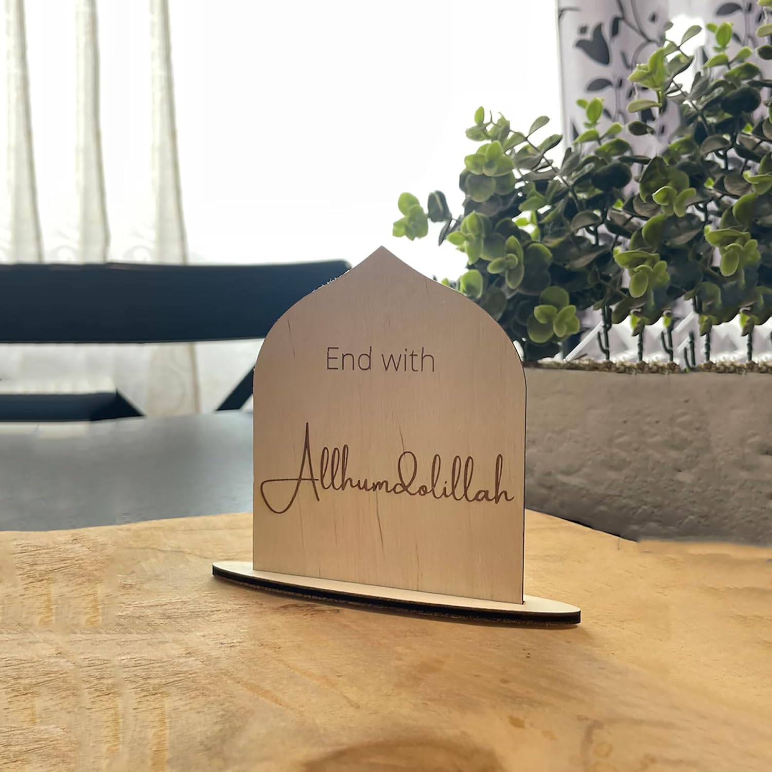 Wooden plaque with 'End with Allhumdolillah' text on a wooden surface.