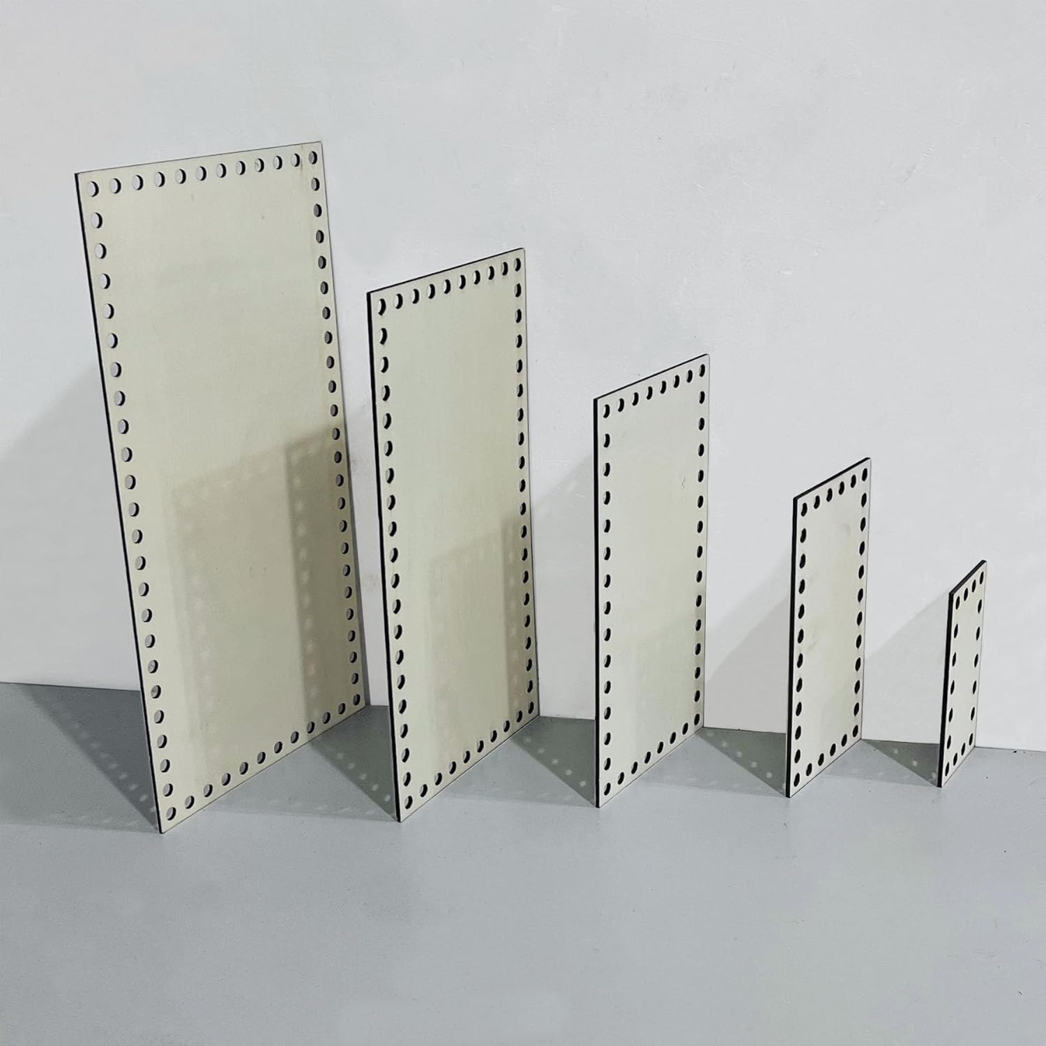 Set of metal display stands with perforated design on a gray surface and light gray background