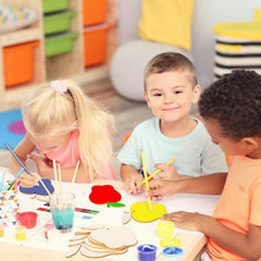 Three children engaged in art activities at a table with colorful materials.