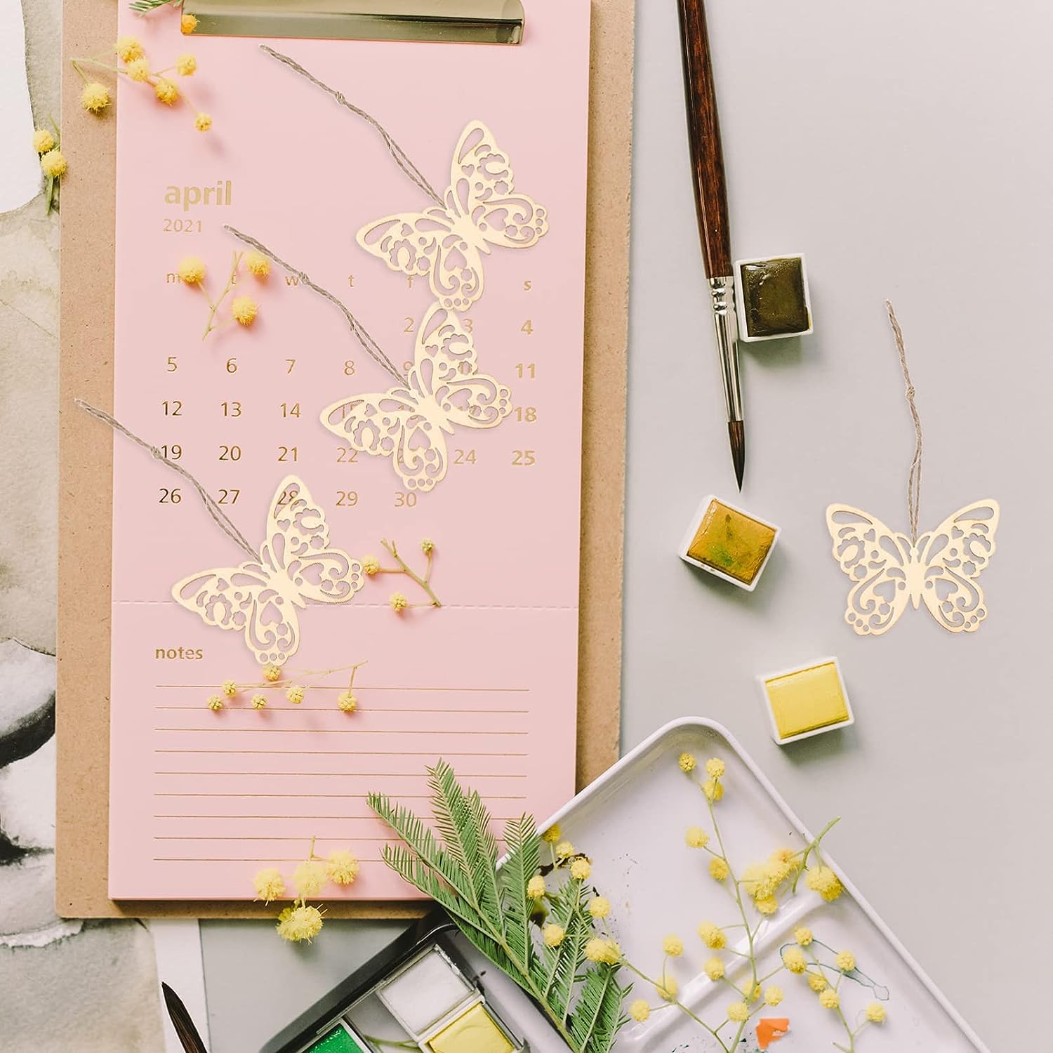 Pink calendar with butterfly designs on a light gray background with stationery items.