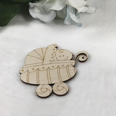 Wooden baby carriage ornament on a white surface with flowers in the background