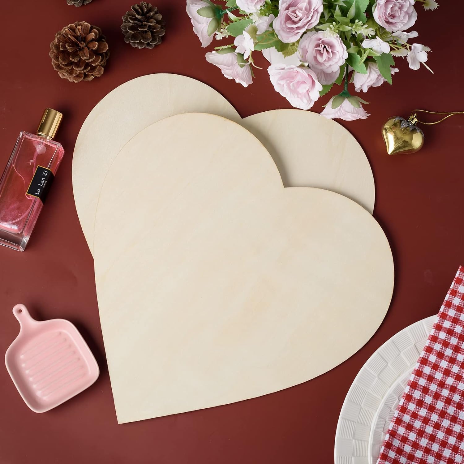 Heart-shaped wooden boards on a red surface with decorative items like flowers and a perfume bottle.