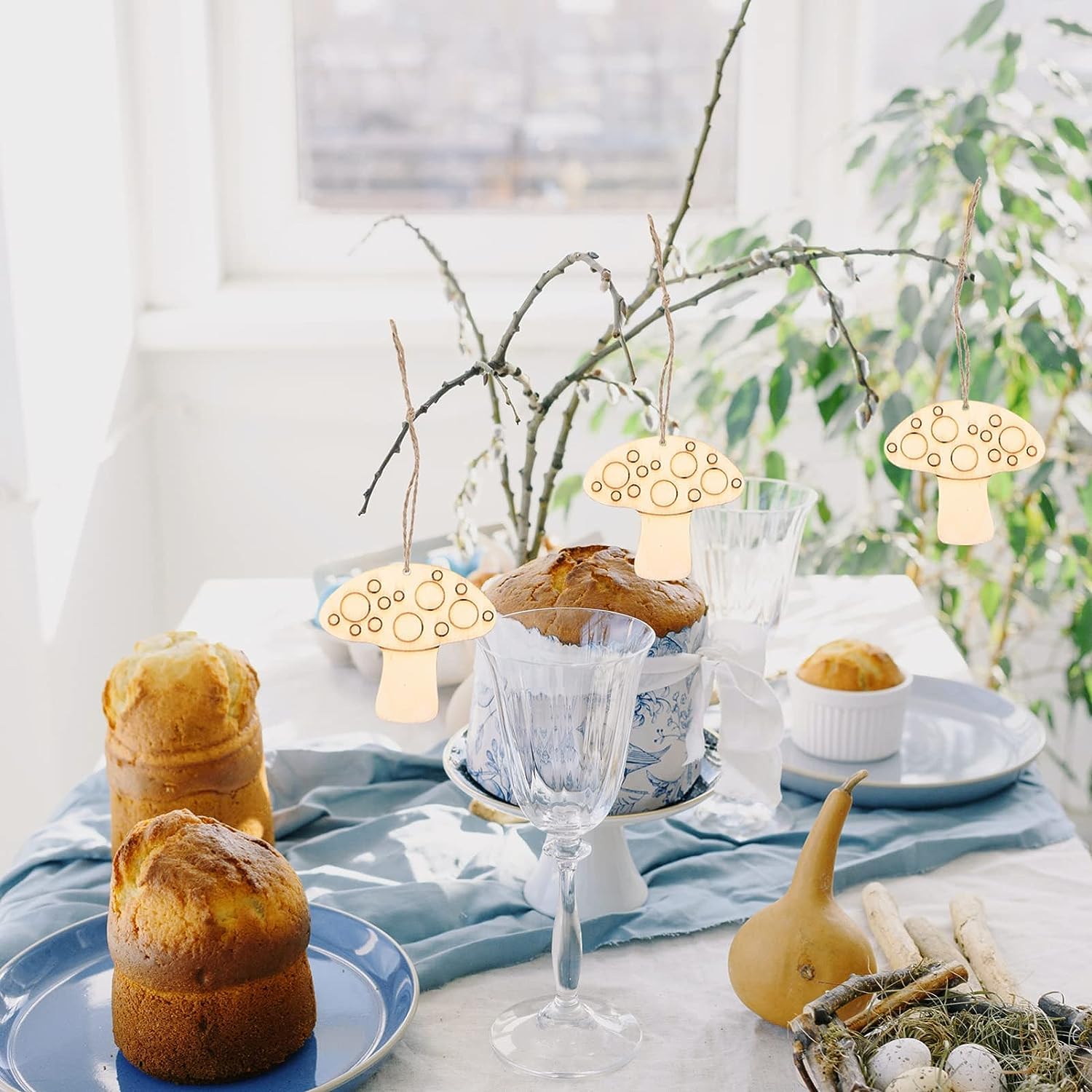 Decorative table setting with pastries, glasses, and small lights on a light background