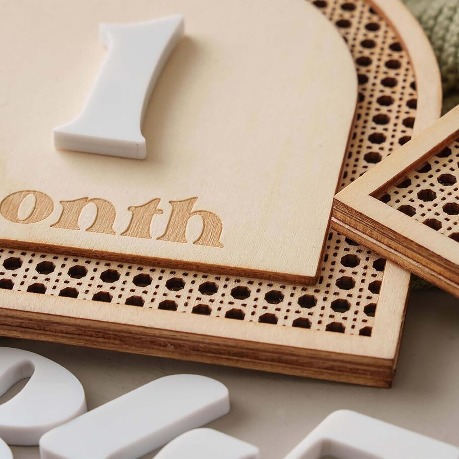 Wooden milestone board with '1 month' engraving and white number pieces on a neutral background