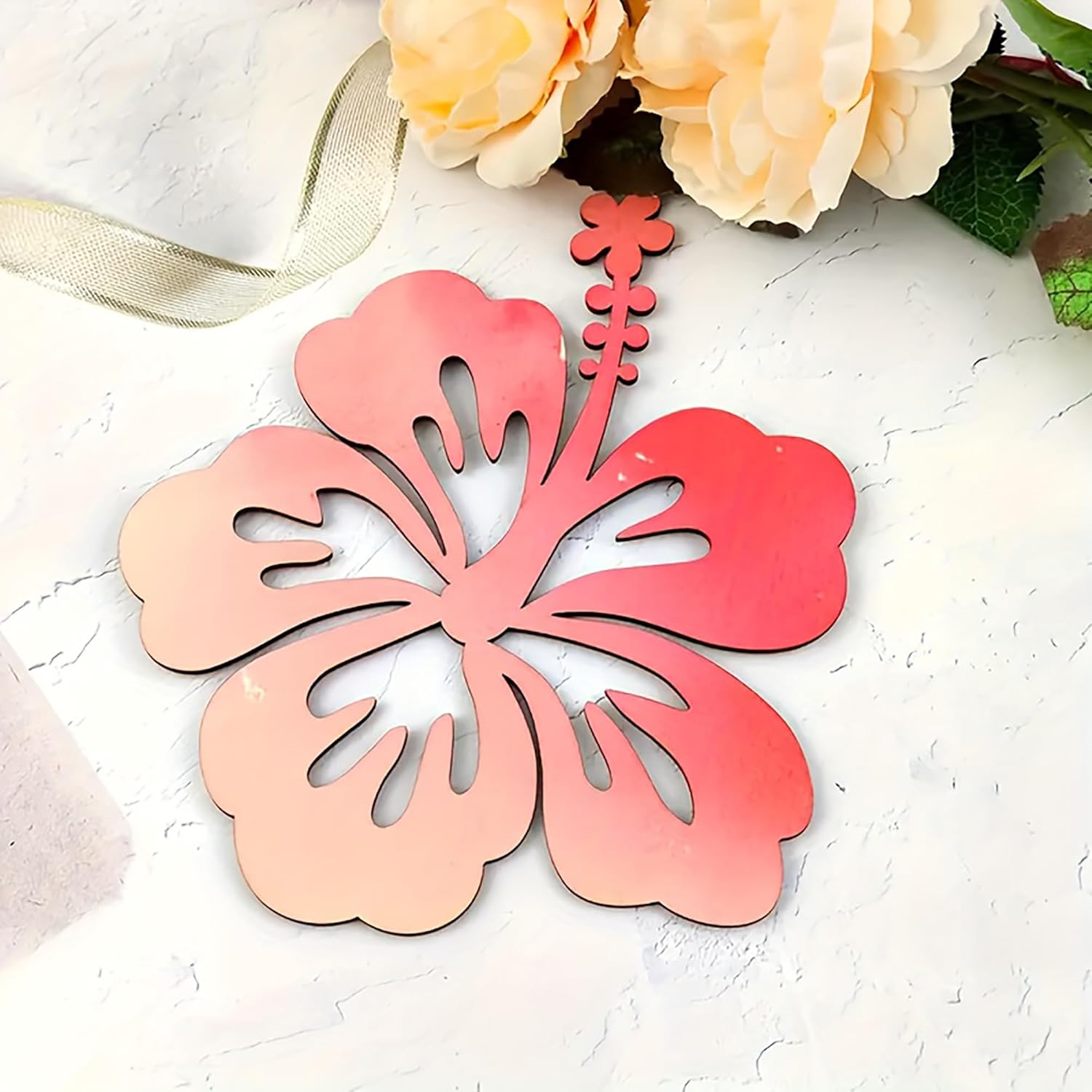 Decorative pink flower-shaped object on a textured white surface with flowers in the background