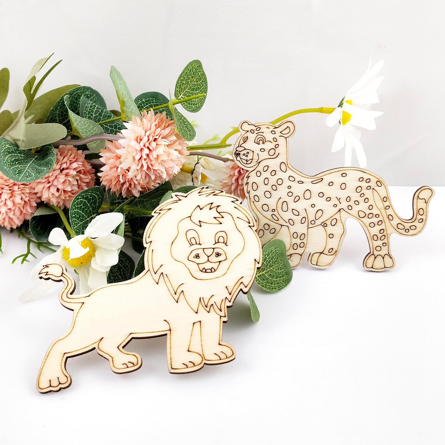 Wooden lion and leopard figurines with flowers on a white background