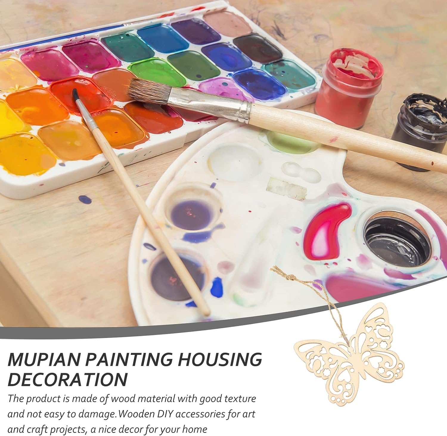 Painting set with watercolors, brushes, and a wooden butterfly decoration on a wooden surface.