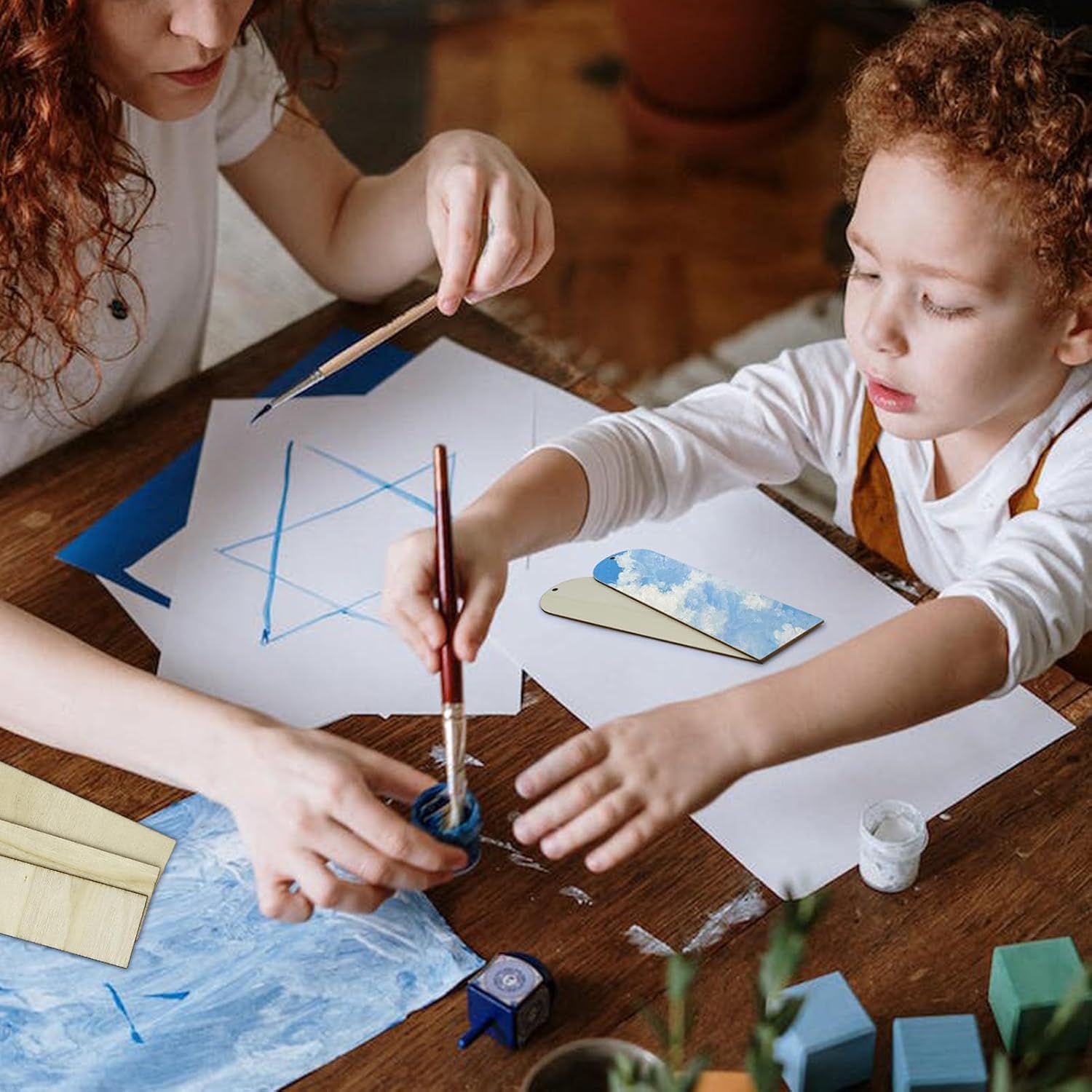 Child and adult engaged in a craft activity at a table with art supplies.