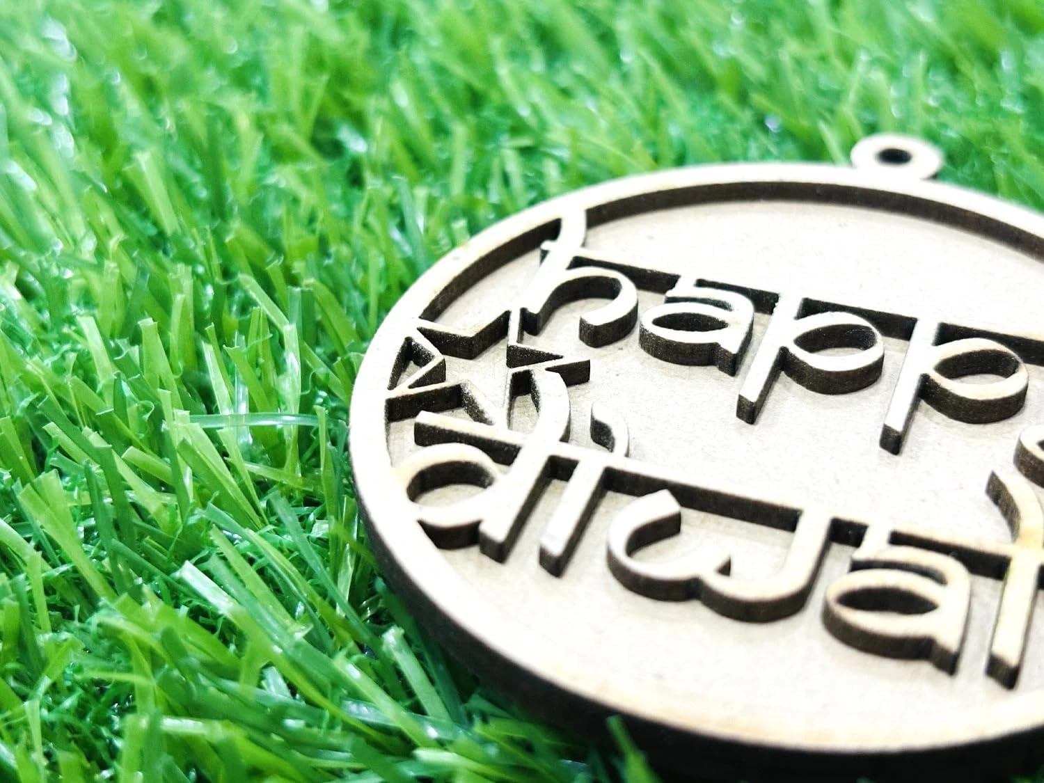 Metallic 'Happy Diwali' ornament on green grass