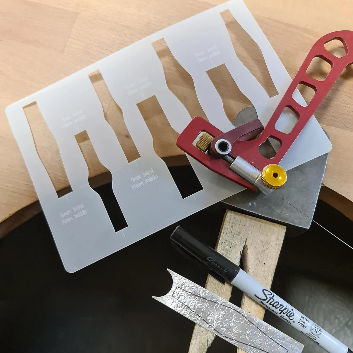 Metal ruler, red tool, and sharpie on a wooden surface