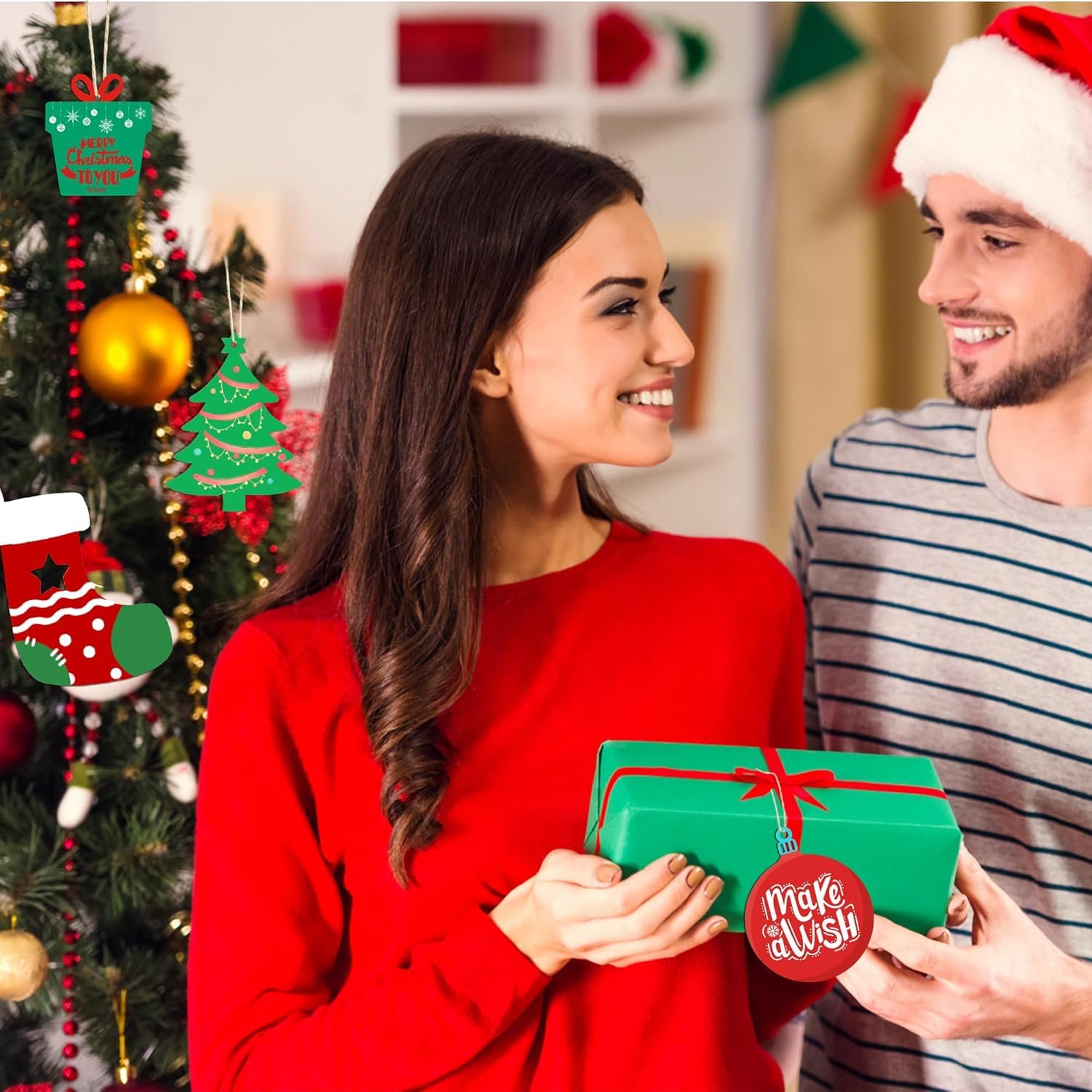 Man and woman exchanging gifts in front of a decorated Christmas tree