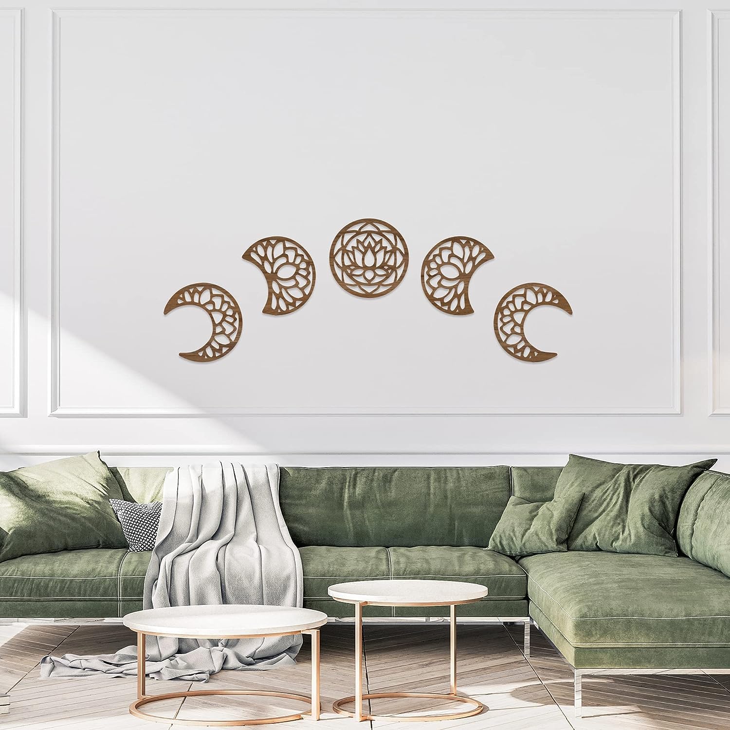 Decorative wall art with moon phases above a green sofa in a living room.