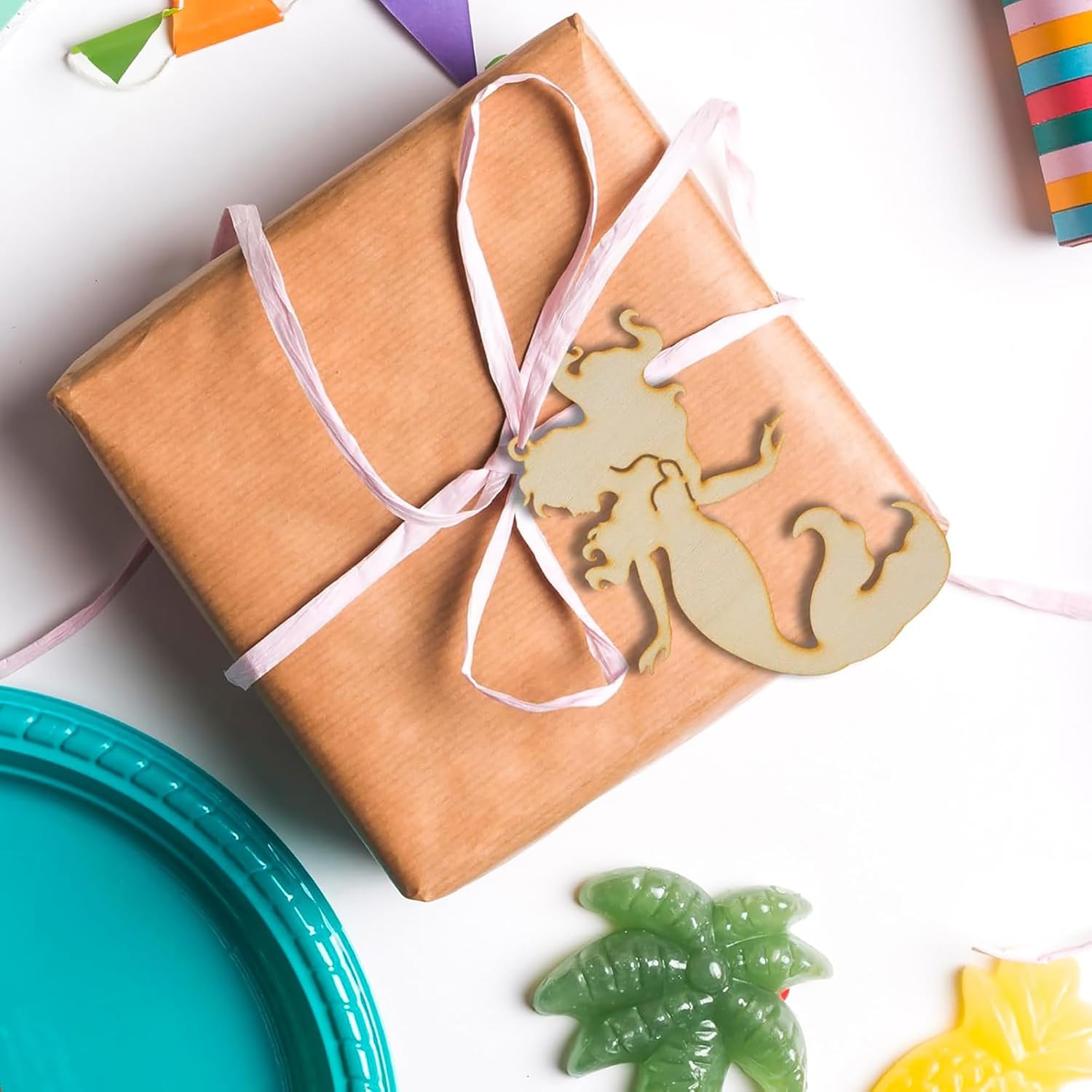 Gift box wrapped in brown paper with a pink ribbon and seahorse ornament on a white background.