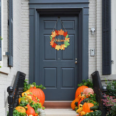 Decorative wreath with pumpkins and autumn leaves on a blue door.