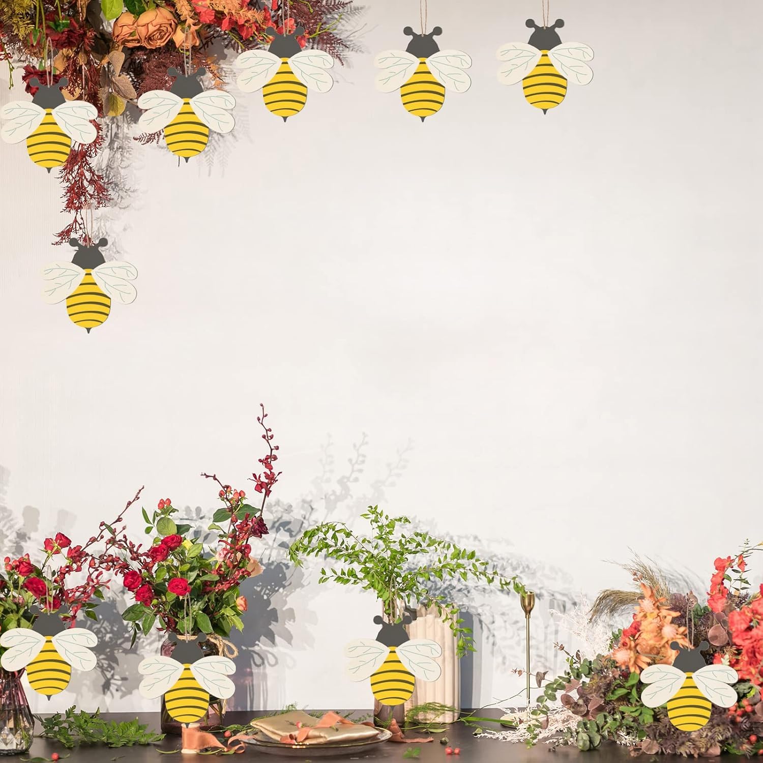 Decorative bees hanging above a table with floral arrangements on a white background