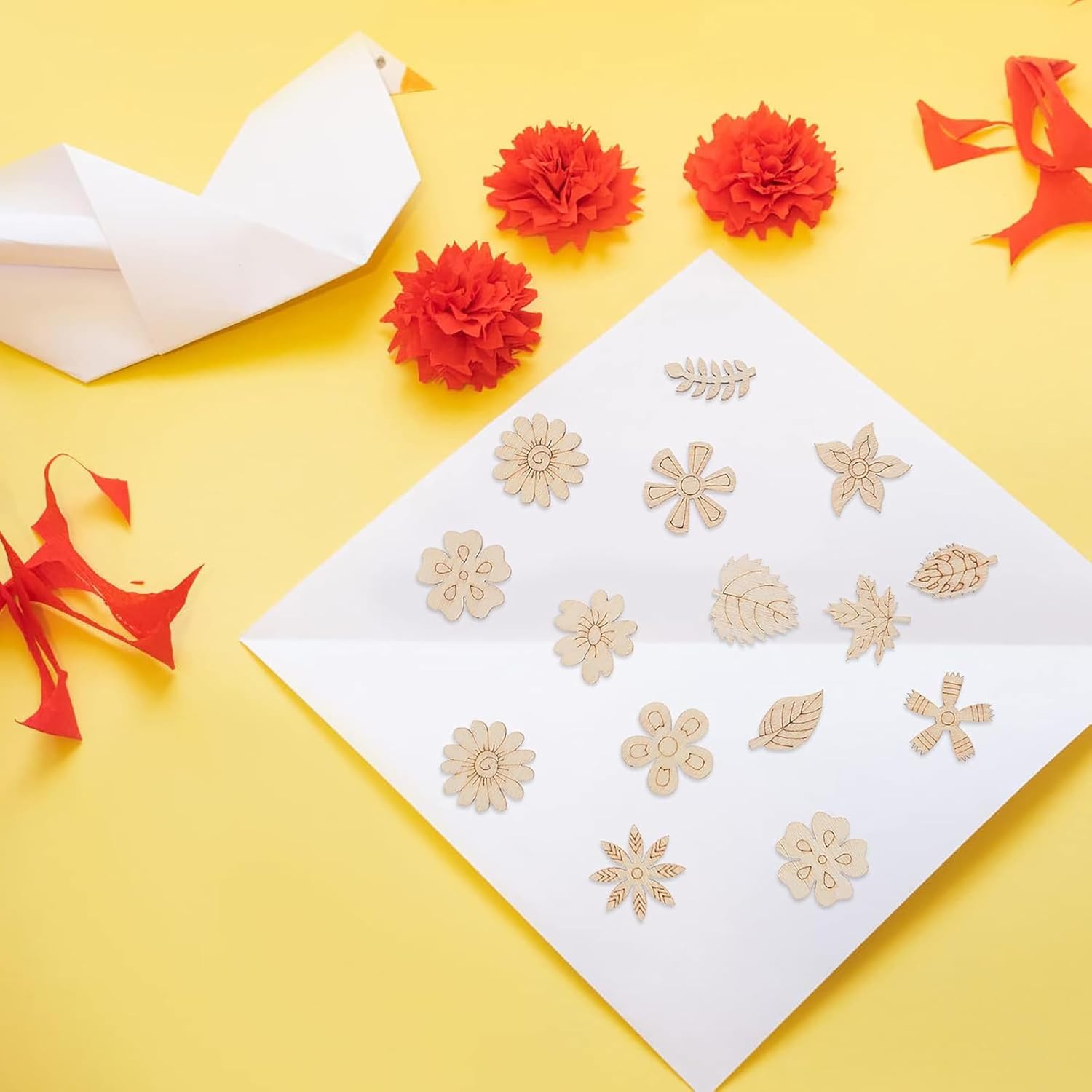 Decorative gold stencils on a white sheet with red flowers and paper birds on a yellow background