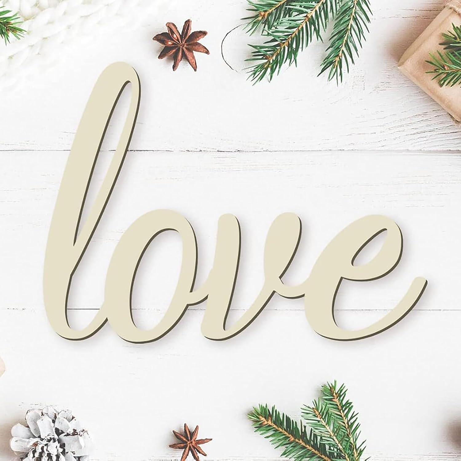 Wooden word 'love' on a white wooden surface with Christmas decorations.