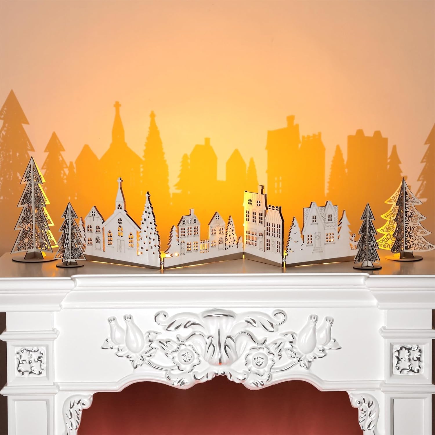 Decorative paper village scene with trees on a mantelpiece against an orange background