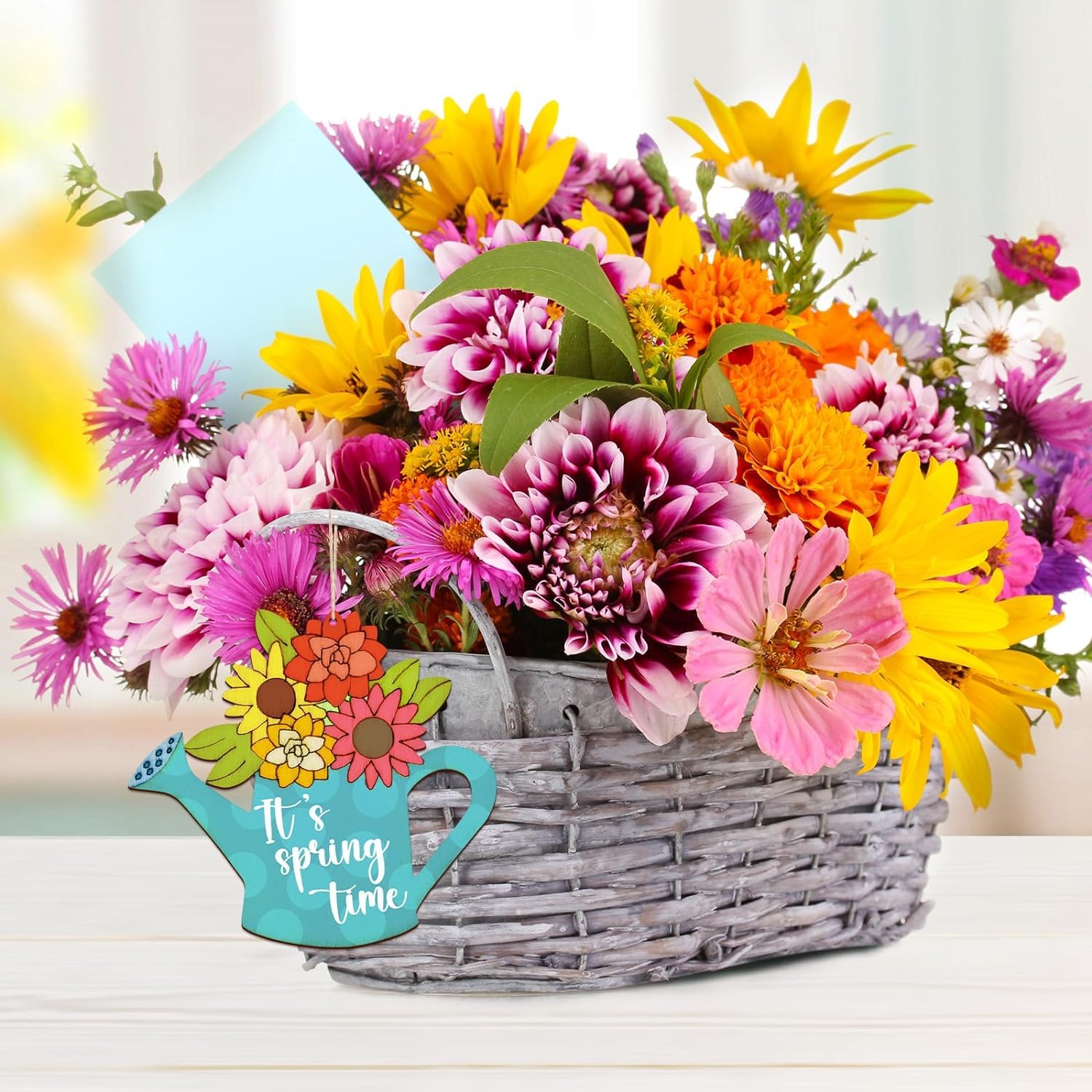 Basket of colorful flowers with a 'It's spring time' sign on a light background