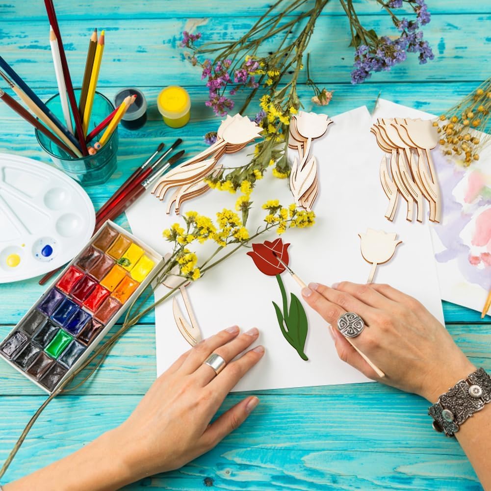 Artistic activity with watercolors, paintbrushes, and floral elements on a blue wooden surface.