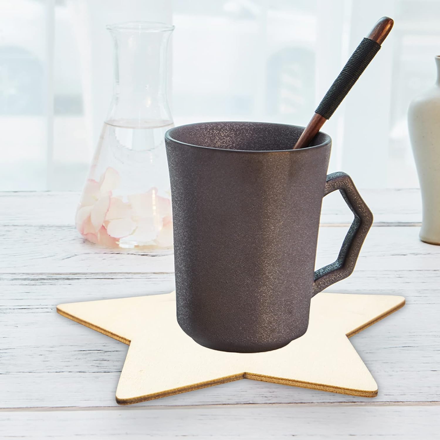 Dark gray mug with a wooden spoon on a star-shaped coaster on a light wooden surface.