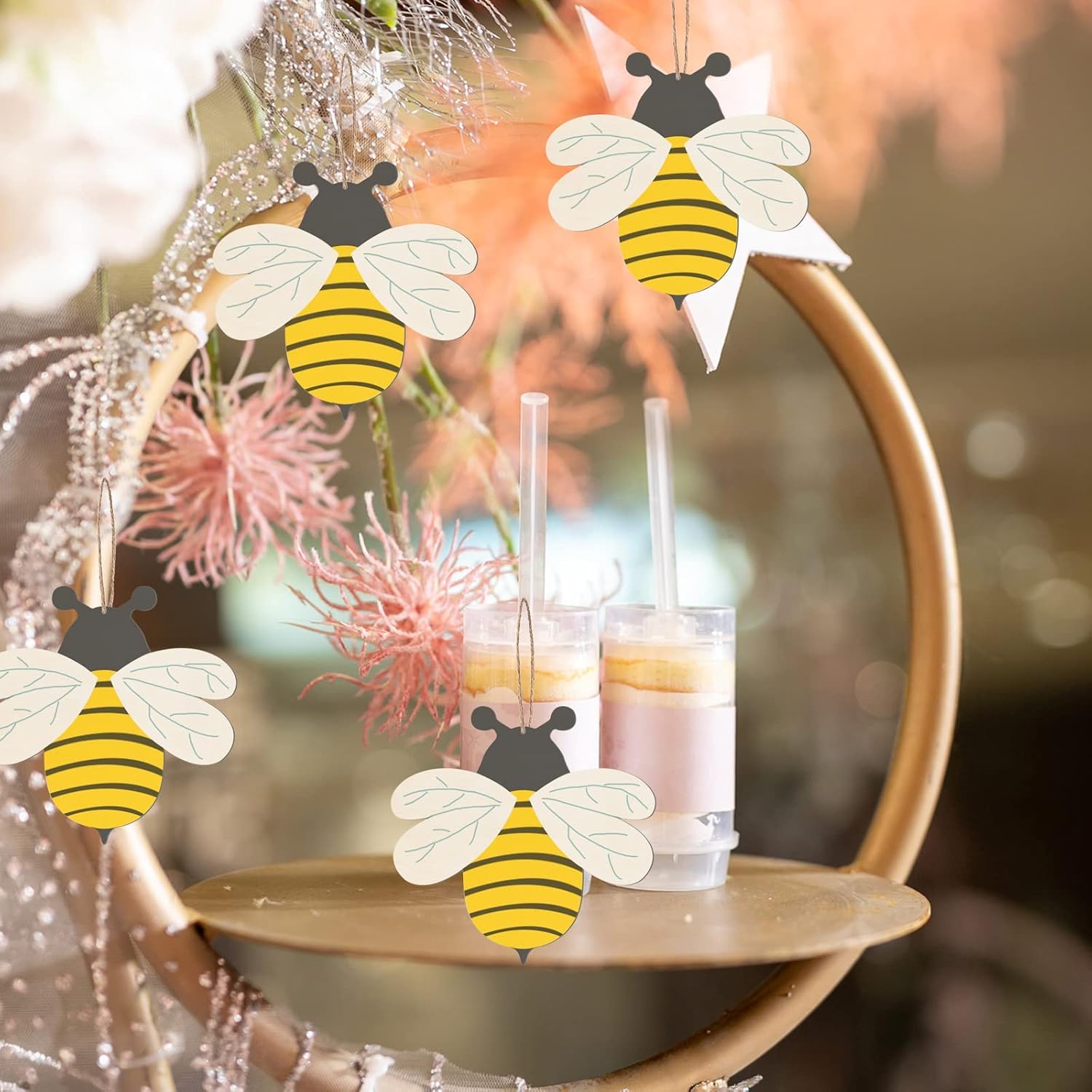 Decorative bee-shaped items hanging above drinks on a table with a blurred background